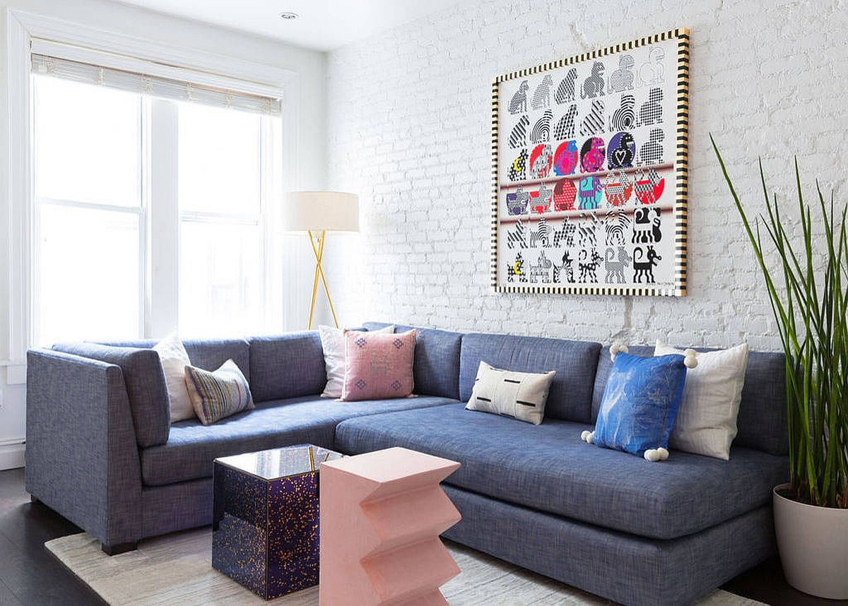 Hình ảnh toàn cảnh phòng khách nhỏ màu trắng sử dụng sofa xanh dương nhạt, tranh treo tường màu sắc, phụ kiện màu hồng san hô