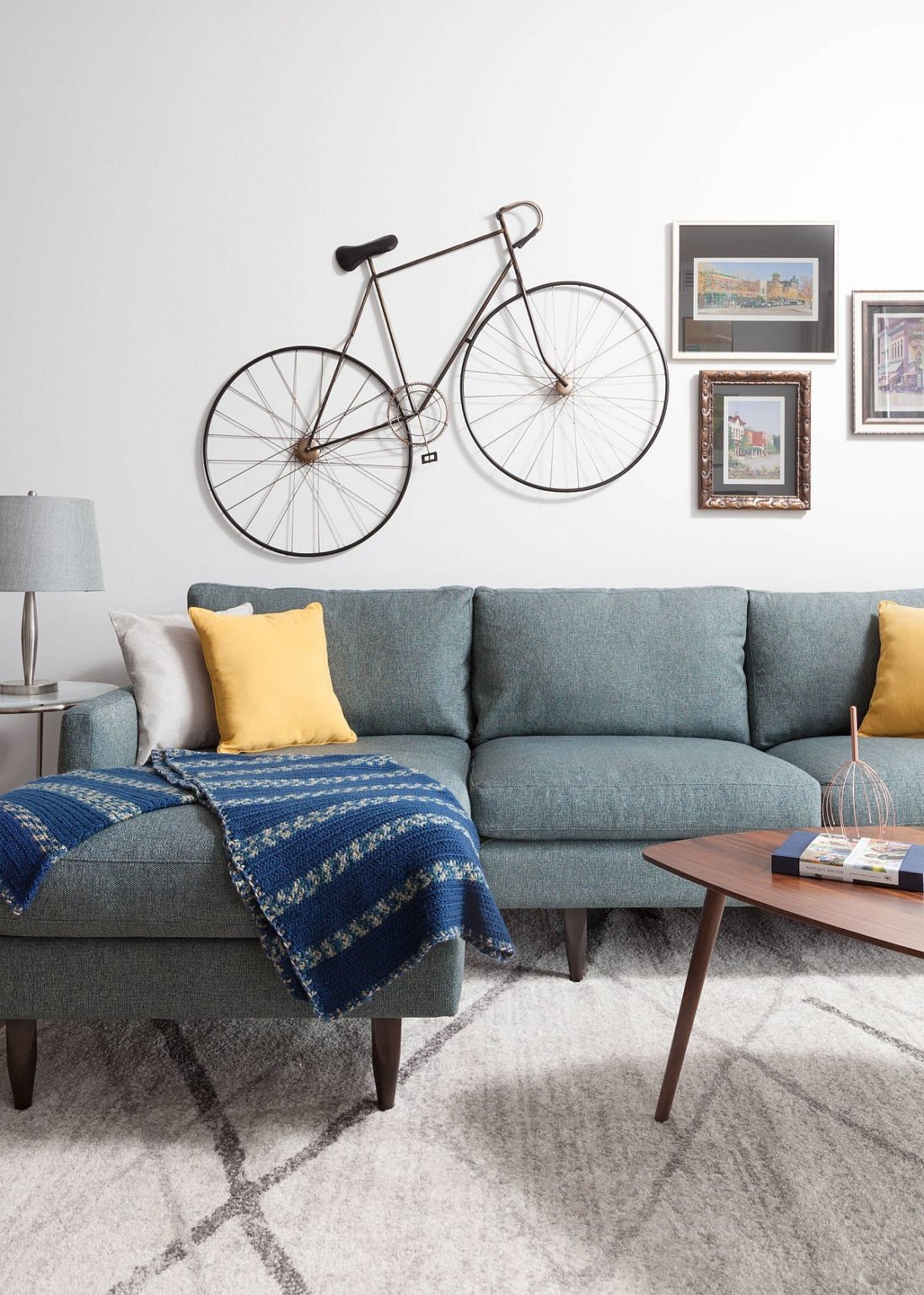 Hình ảnh cận cảnh phòng khách nhỏ với ghế sofa màu xanh dương, gối tựa màu vàng nổi bật, thảm trải xám