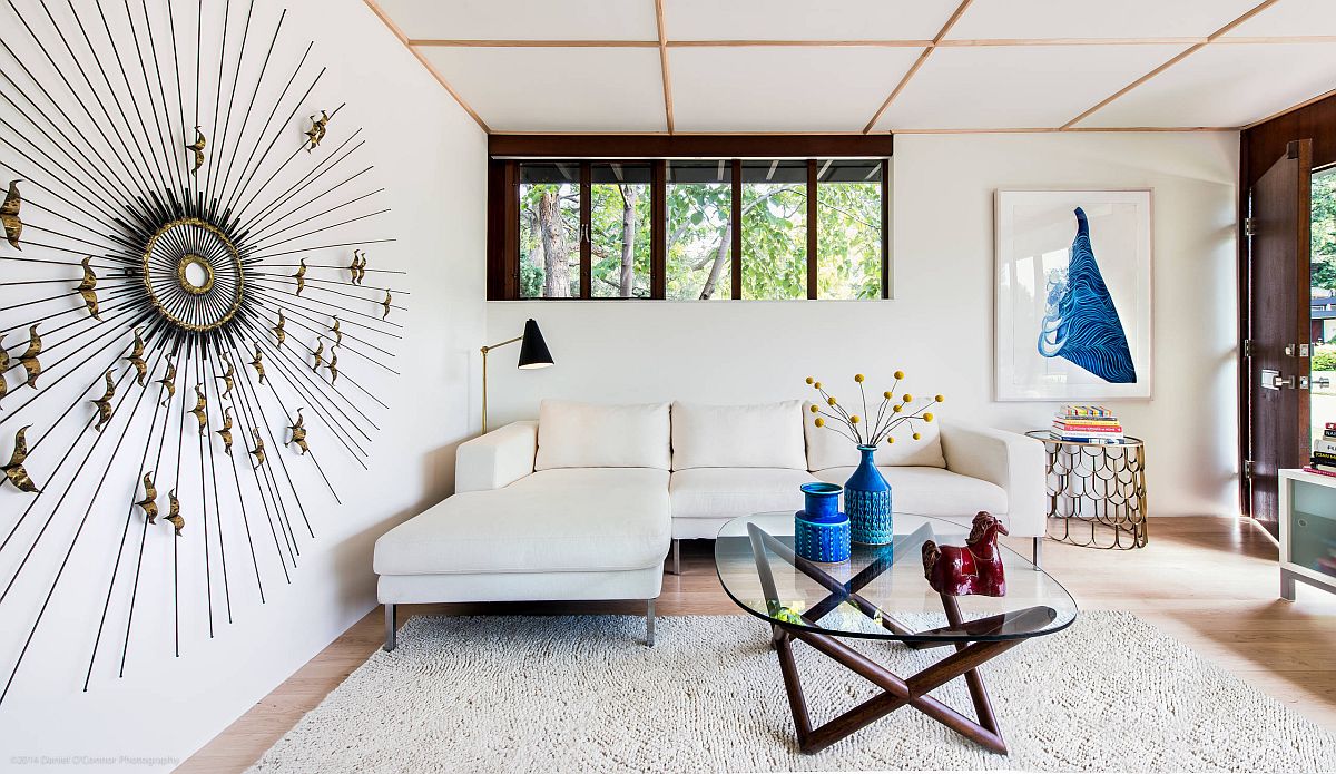 Hình ảnh toàn cảnh phòng khách màu trắng có trần thấp, nổi bật với họa tiết trang trí mặt trời trên tường nhà.