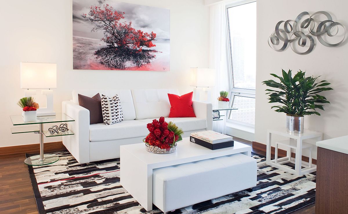 Toàn cảnh phòng khách nhỏ màu trắng được nhấn nhá bởi gối tựa sofa, tranh treo tường màu đỏ ấn tượng