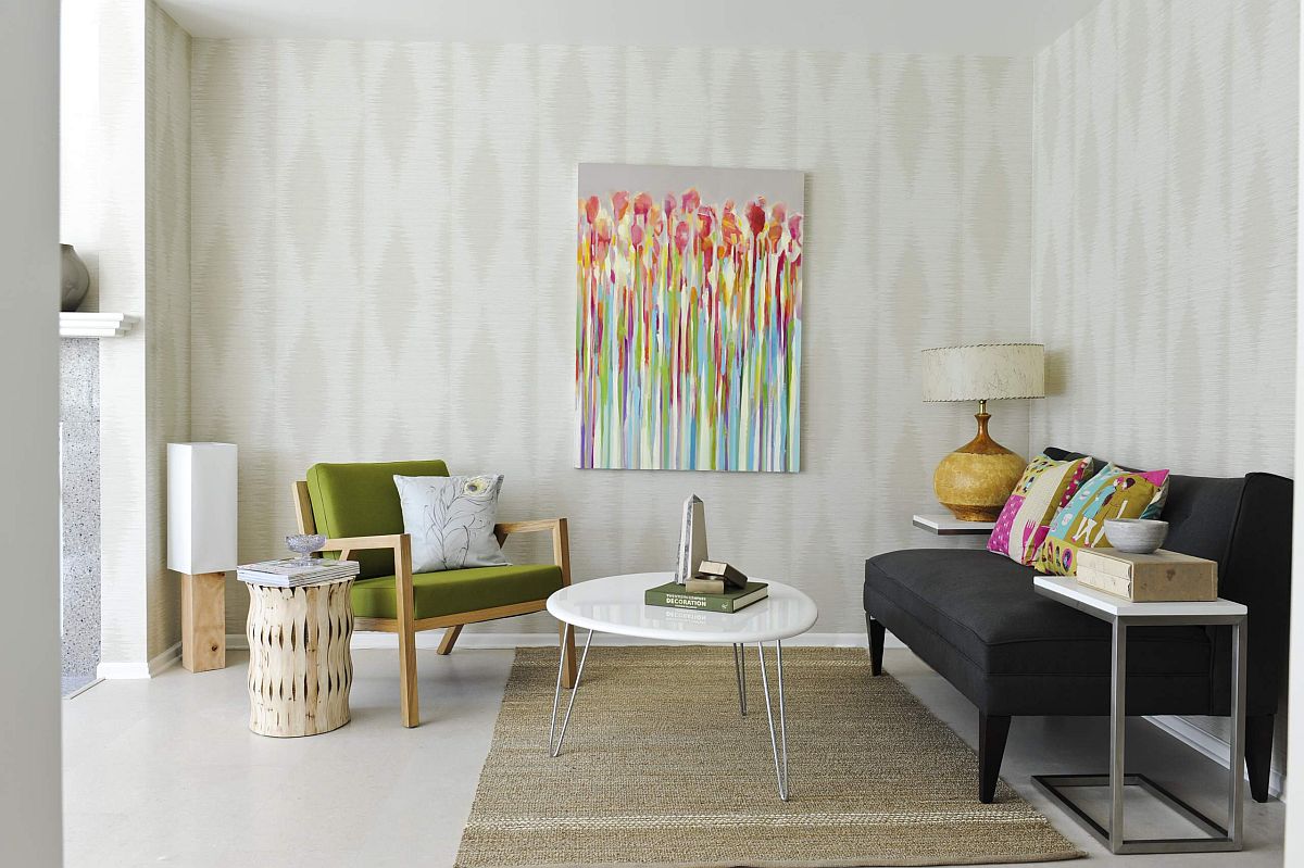 Hình ảnh phòng khách nhỏ màu trắng với sofa đen, ghế bành xanh lá, tranh treo tường nghệ thuật