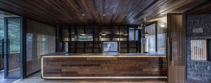 Hình ảnh toàn cảnh phòng bếp trong khách sạn gỗ với tường, trần, đảo bếp đều được làm bằng gỗ sẫm màu