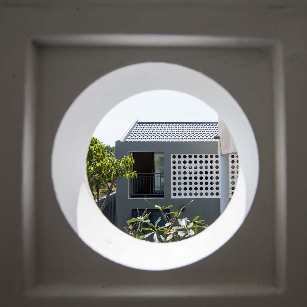 Hình ảnh cận cảnh khung cửa sổ tròn mềm mại mở ra khối nhà bên ngoài