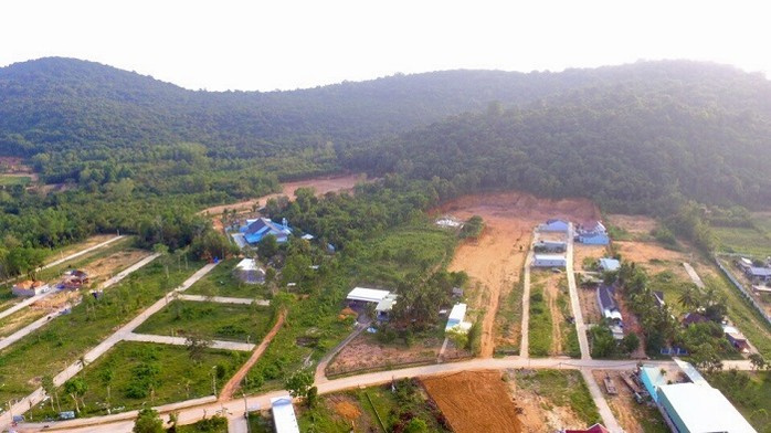 Hình ảnh một khu đất nông nghiệp nhìn từ trên cao với thưa thớt nhà dân xen kẽ cây xanh, xung quanh là đồi núi