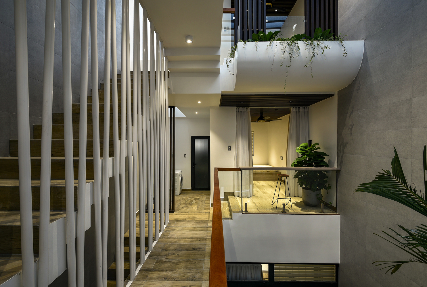 Hình ảnh các phòng riêng trong nhà phố đều có cửa mở ra khoảng thông tầng thoáng sáng, trồng cây xanh, cạnh đó là cầu thang với lan can độc đáo