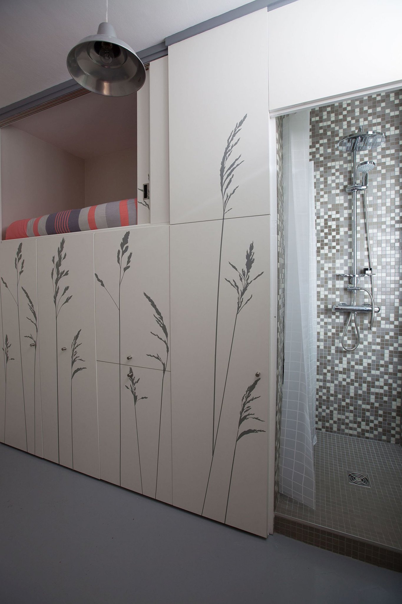 Hình ảnh một góc phòng tắm sử dụng vòi hoa sen, tường ốp gạch, rèm cửa kể ô màu trắng.
