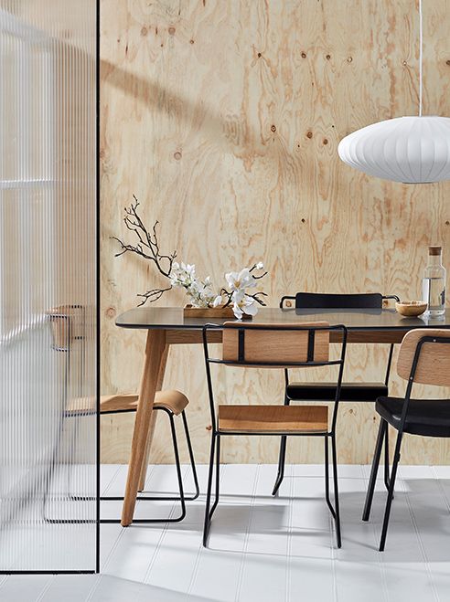 Hình ảnh một góc phòng ăn với mảng tường ốp gỗ màu sáng ấm áp, bàn ghế kiểu dáng thanh mảnh, vách kính trong suốt