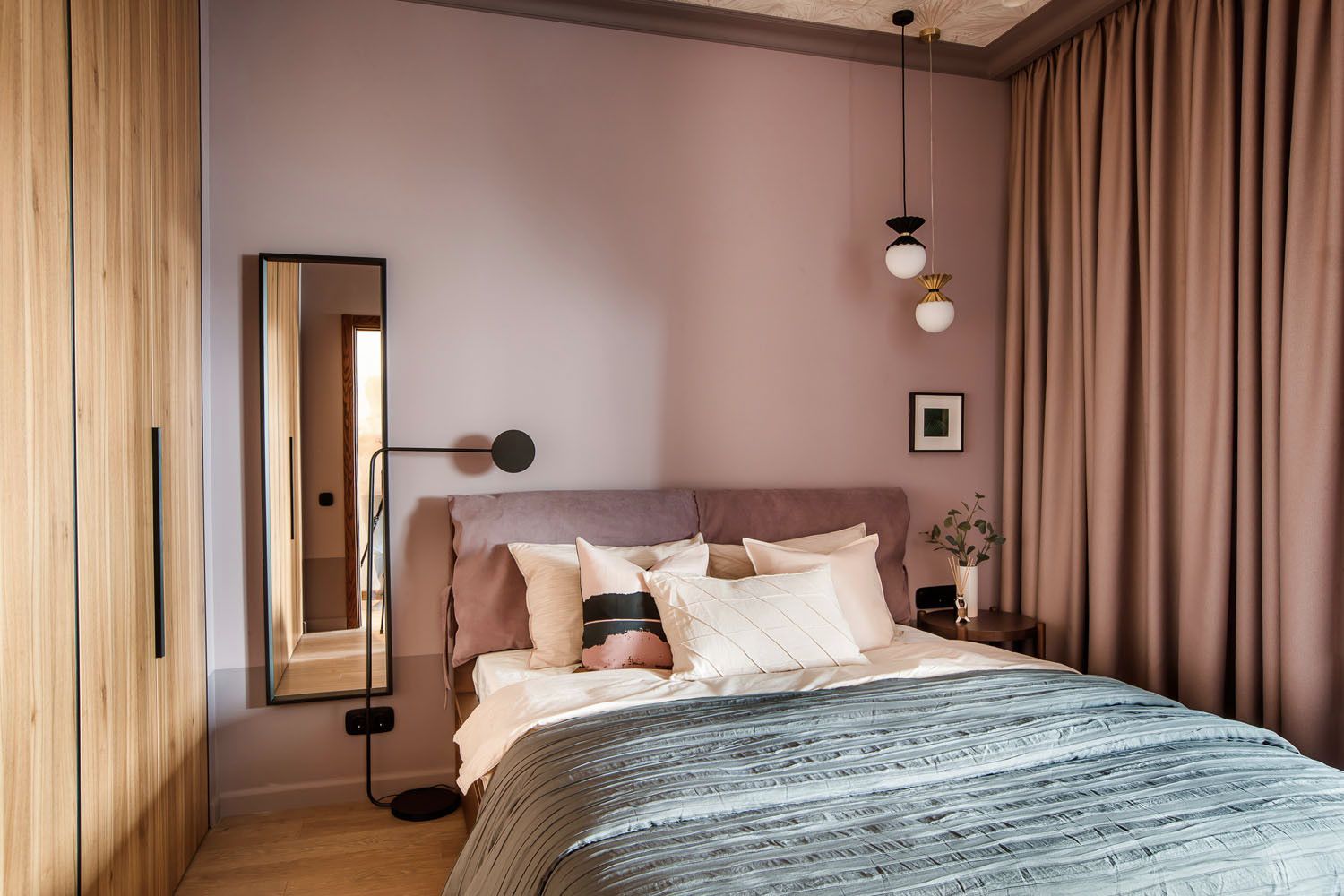 Hình ảnh phòng ngủ phong cách Bắc Âu với tường sơn màu hồng pastel, giường nệm màu trắng, cạnh đó là tủ gỗ lớn