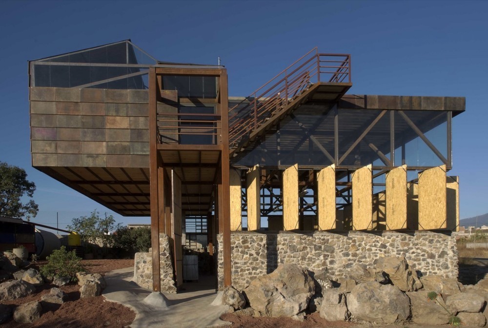 Hình ảnh cận cảnh một ngôi nhà làm từ vật liệu tái chế với móng đá, khung kim loại, gỗ