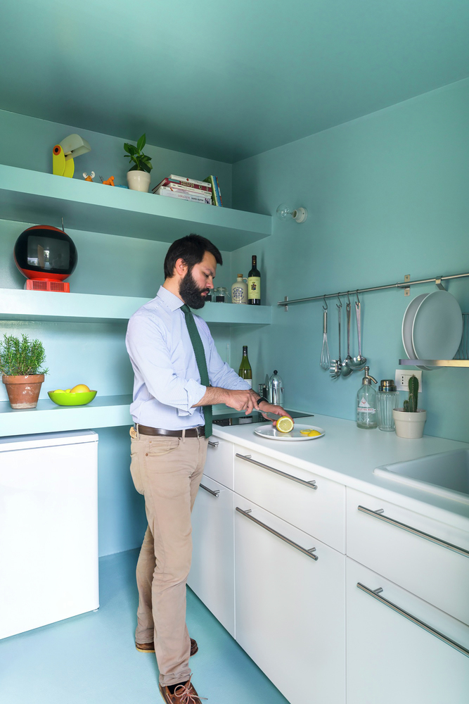 Hình ảnh người đàn ông đắt cắt chanh trong phòng bếp màu xanh dương nhạt