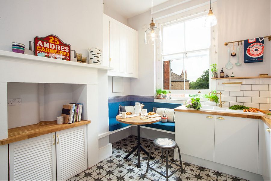 Hình ảnh góc ăn sáng trong bếp với ghễ dài áp tường lót nệm màu xanh dương, bàn gỗ tròn