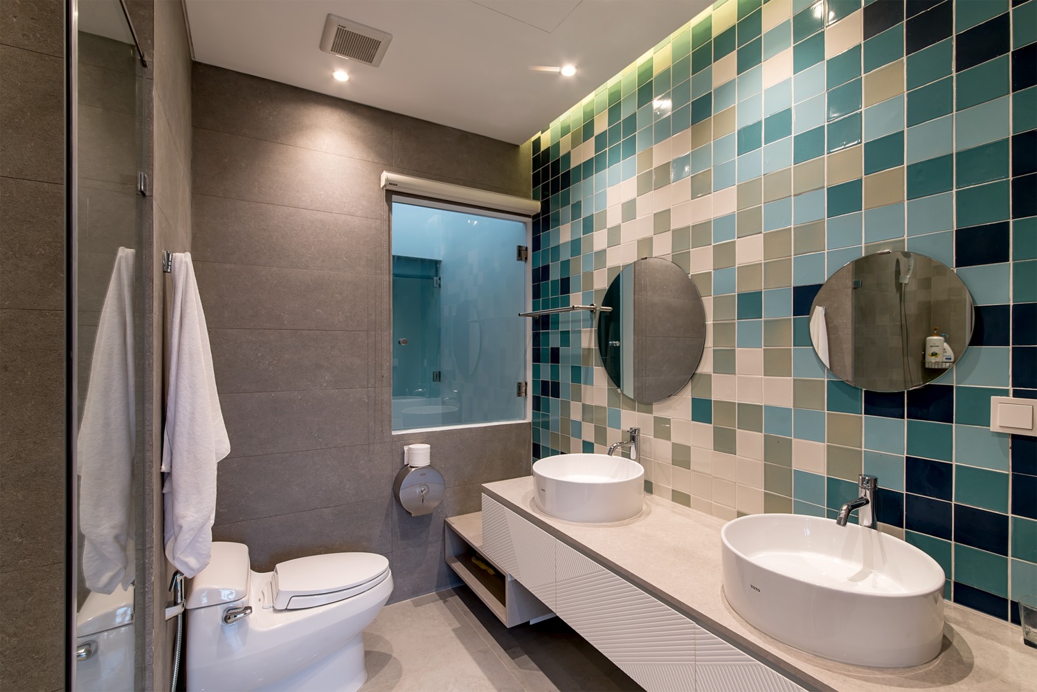 Hình ảnh phòng vệ sinh nổi bật với tường ốp gạch men, bồn rửa đôi, bộ đôi gương soi gắn tường
