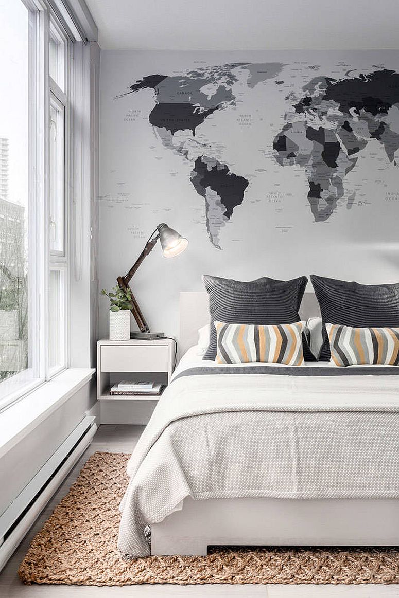Hình ảnh một góc phòng ngủ màu đen - trắng với giường kê cạnh cửa sổ kính, đầu giường trang trí bản đồ thế giới