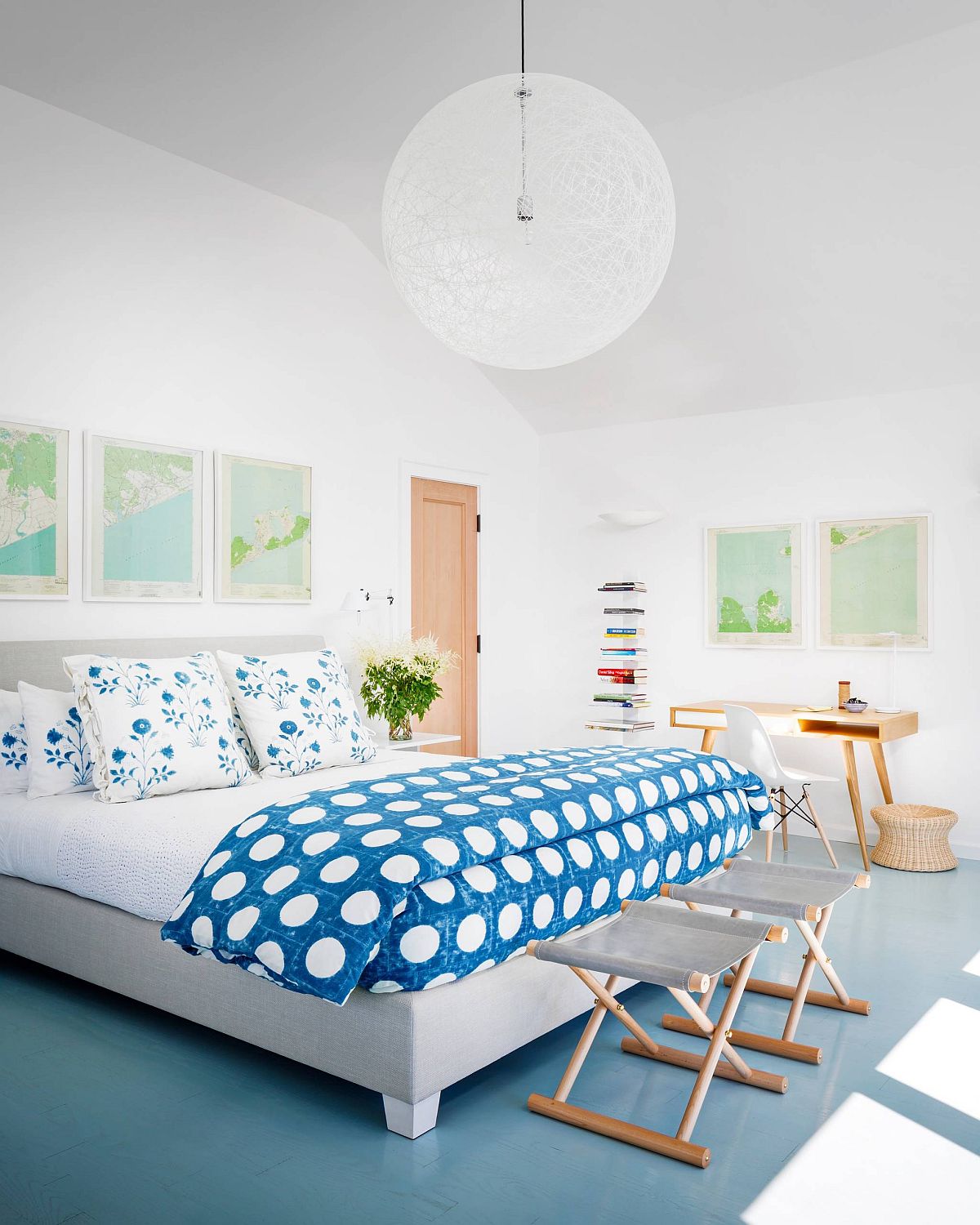 Hình ảnh phòng ngủ phong cách bãi biển với gam màu xanh dương chủ đạo, gối họa tiết hoa bắt mắt, phụ kiện trang trí là bản đồ