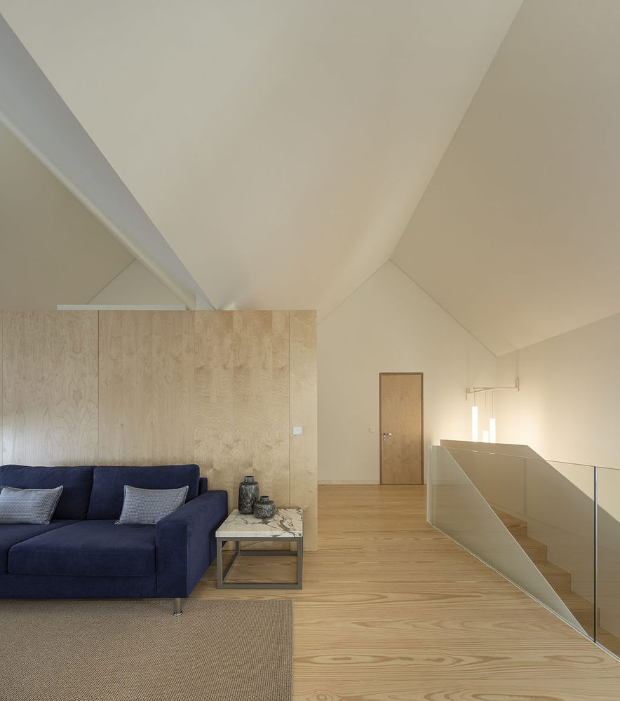 Hình ảnh một góc phòng khách trong nhà 3 tầng có thiết kế tối giản với sofa màu xanh dương, sàn gỗ