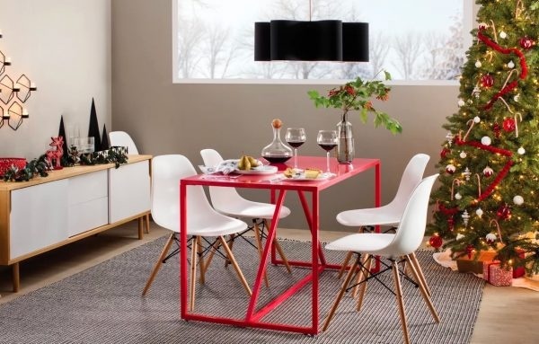 Hình ảnh cận cảnh mẫu bàn ăn màu đỏ kết hợp ghế ngồi màu trắng, cạnh đó là cây thông Noel lớn