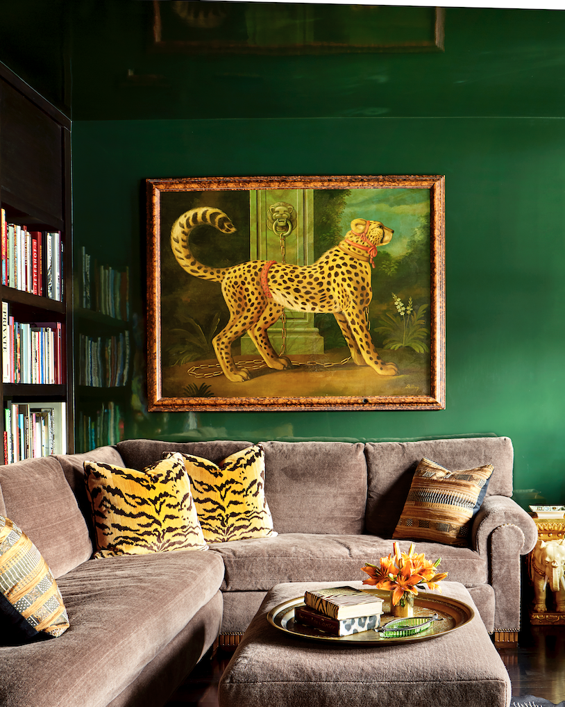 Hình ảnh một góc phòng khách với tường sơn màu xanh lá đậm, ghế sofa màu tím oải hương, gối tựa màu sắc