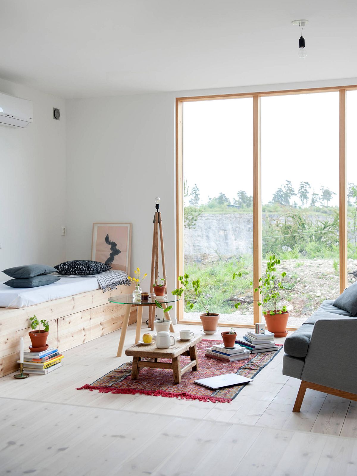 Hình ảnh phòng khách tối giản nổi bật với những chậu cây đất nung nhỏ xinh, sofa xám đối diện giường thư giãn.