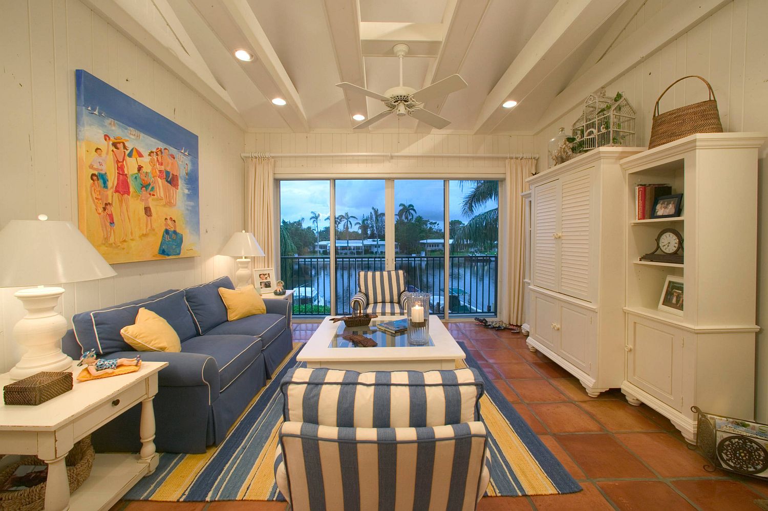 Hình ảnh phòng khách phong cách bãi biển với sofa màu xanh dương, ghế bọc nệm kẻ sọc
