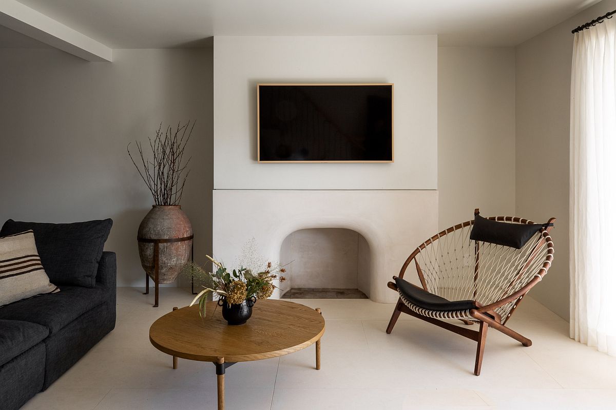 Hình ảnh phòng khách phong cách Địa Trung Hải với sofa đen, gối tựa kẻ sọc, bình hoa đất nung màu tối đặt ở góc