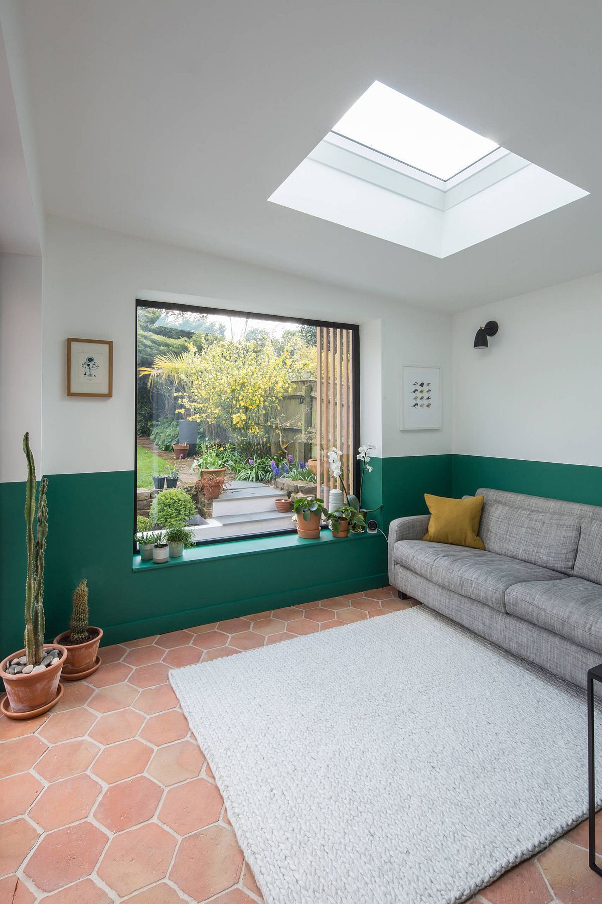 Hình ảnh phòng khách đơn giản với sofa xám, sàn gạch nung, tường sơn màu xanh lá