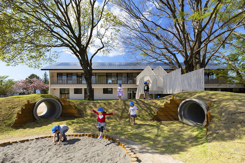 Hình ảnh các bé đang chơi đùa trong khuôn viên trường mầm non ở Nhật dưới tán cây cổ thụ