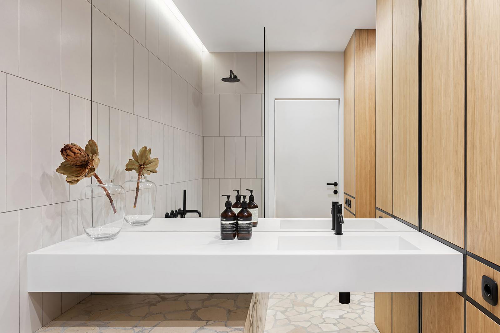Hình ảnh cận cảnh một góc phòng tắm hiện đại với gương lớn gắn tường, bồn rửa hình chữ nhật màu trắng