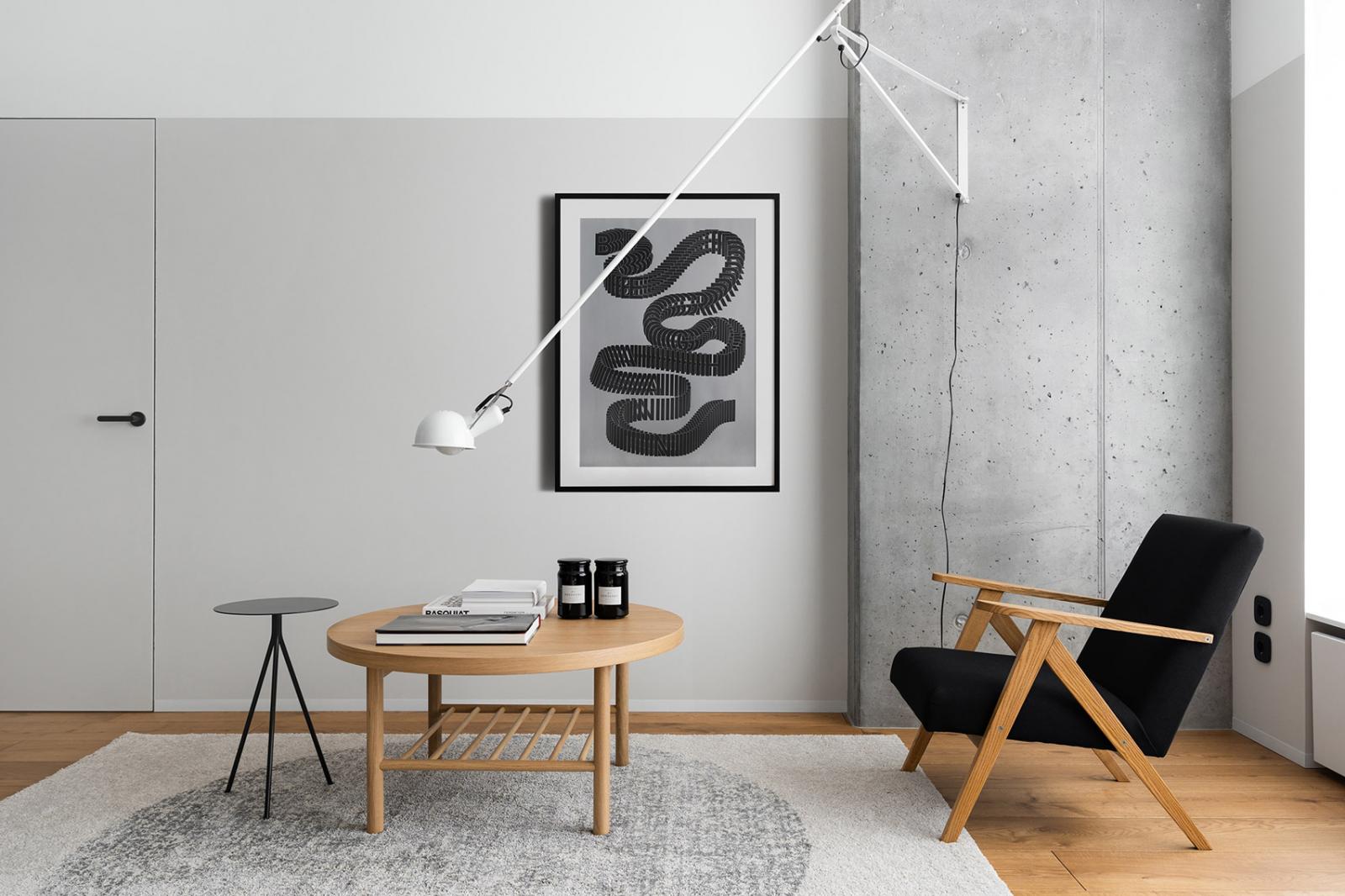 Hình ảnh phòng khách căn hộ 65m2 với bàn trà gỗ hình tròn, ghế tựa bọc nệm đen, tranh treo tường ấn tượng