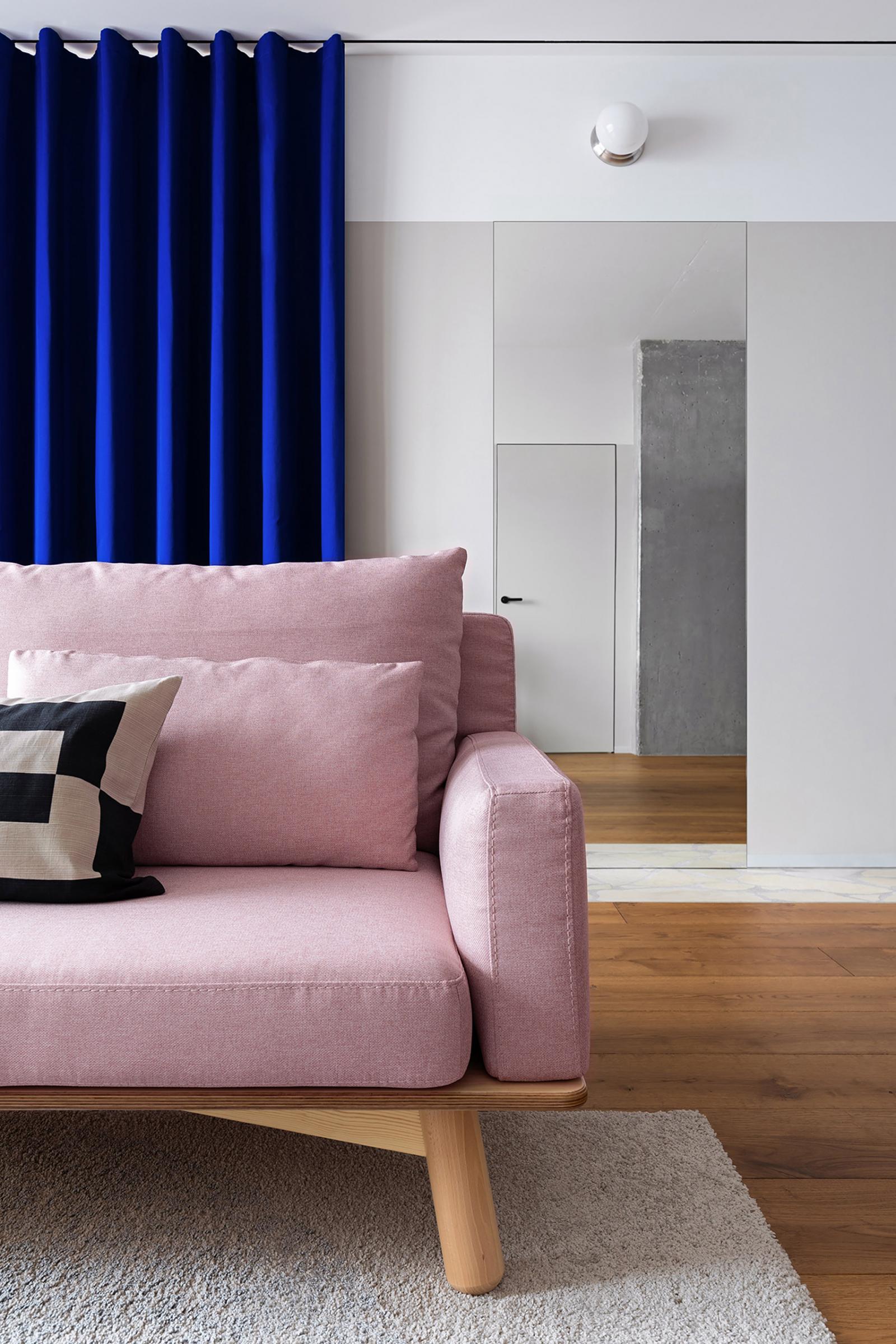 Hình ảnh một góc phòng khách căn hộ với sofa màu hồng tương phản rèm cửa màu xanh coban