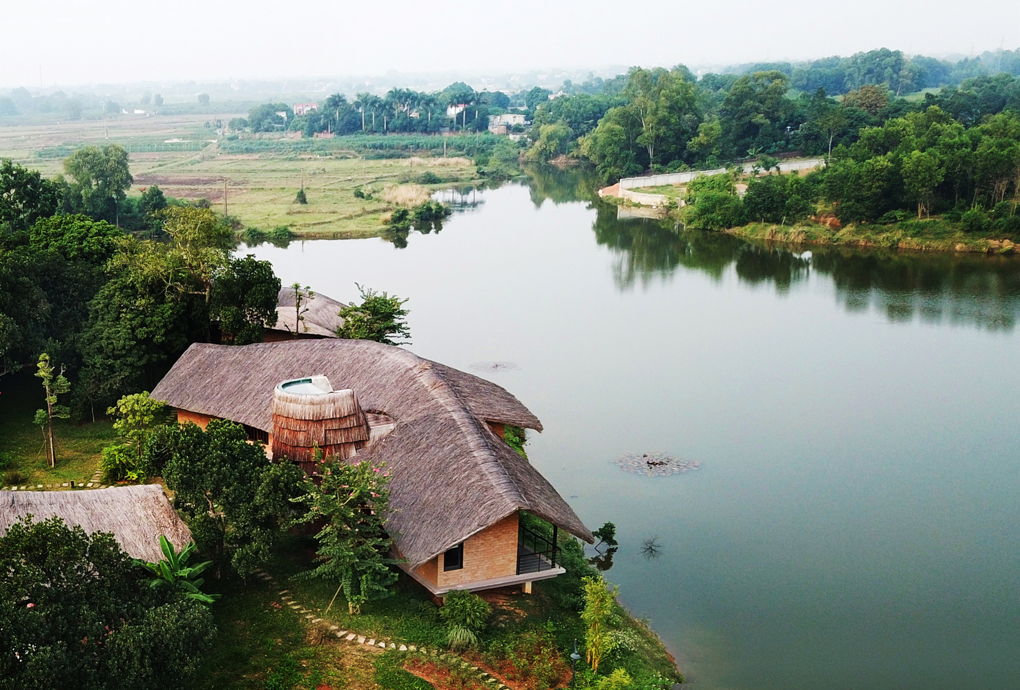 Hình ảnh toàn cảnh ngôi nhà ông Hùng nhìn từ trên cao, xung quanh là cây cối, sông nước yên bình