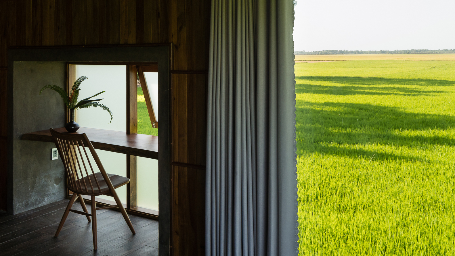 Cận cảnh góc ngồi thư giãn cạnh khung cửa sổ kính hướng nhìn ra đồng lúa xanh mướt