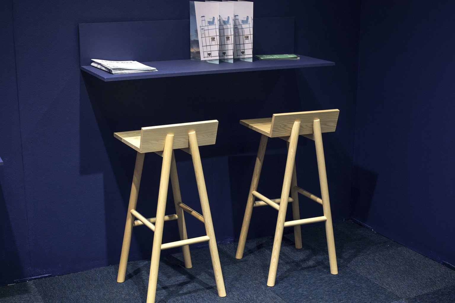 Cận cảnh góc làm viêc với bàn nhỏ gắn tường sơn xanh than, ghế bar bằng gỗ màu trắng