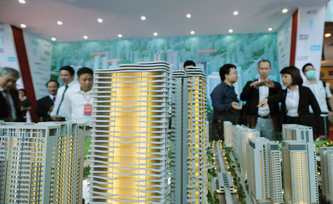 Hình ảnh cận cảnh sa bàn một dự án bất động sản gồm nhiều tòa nhà cao tầng, xung quanh có nhiều người đứng xem.
