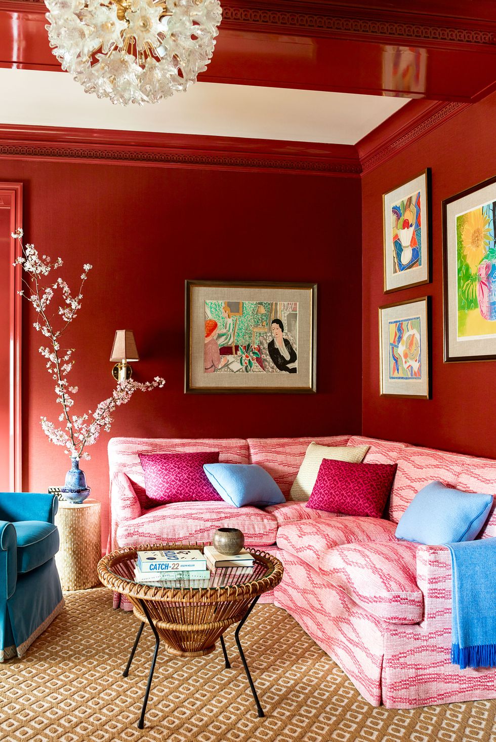 Hình ảnh một góc phòng khách với tường sơn đỏ cam, tranh treo tường bắt mắt, đèn chùm sang trọng