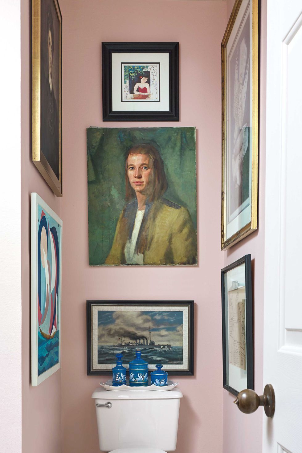 Hình ảnh một góc phòng tắm với tường sơn màu hồng nhạt, bộ tranh chân dung nổi bật