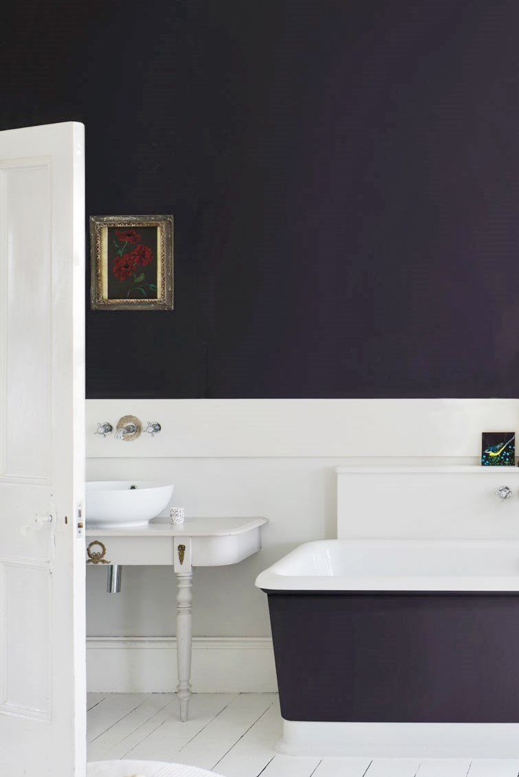 Hình ảnh một góc phòng tắm với mảng tường lớn màu cà tím cùng tông với bồn tắm nằm