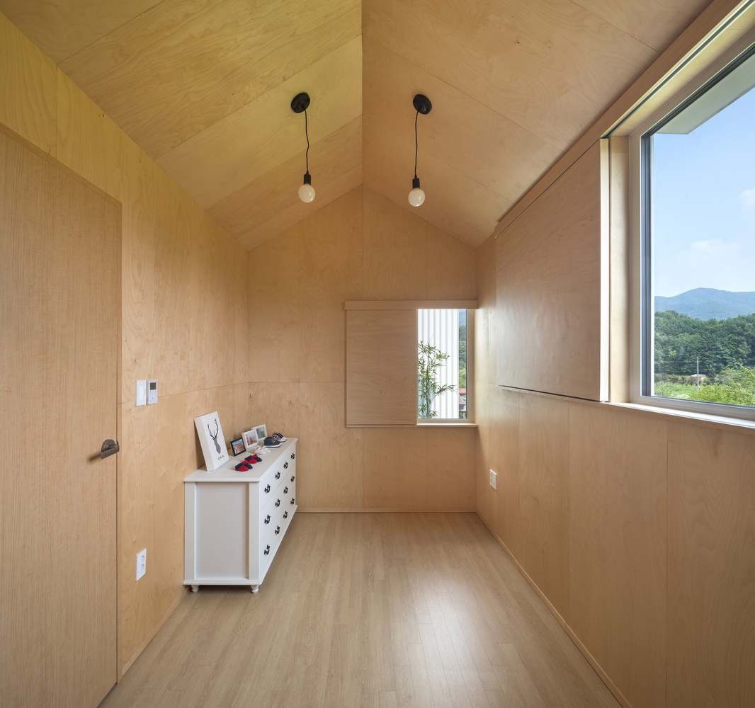 Hình ảnh một căn phòng với tường và trần ốp gỗ, tủ ngăn kéo màu trắng, đèn thả sợi đốt