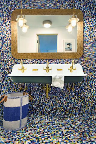 Hình ảnh một góc phòng tắm với tường và sàn ốp gạch kích thước nhỏ tông màu tươi sáng, khung gương lớn, bồn rửa sơn xanh