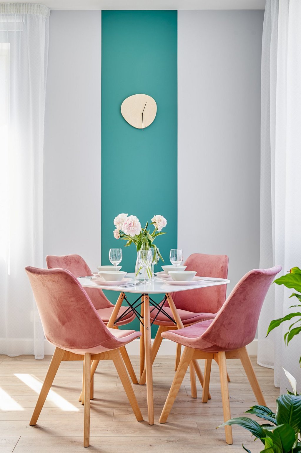 Hình ảnh phòng ăn nhỏ với ghế hồng pastel bao quanh bàn tròn, cạnh đó là bức tường xanh dương tạo điểm nhấn