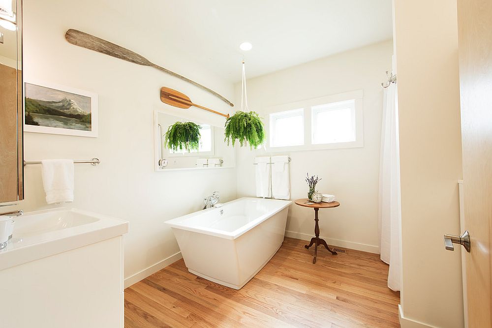 Hình ảnh phòng tắm màu trắng rộng thoáng với sàn lát gỗ, chậu cây xanh tạo điểm nhấn