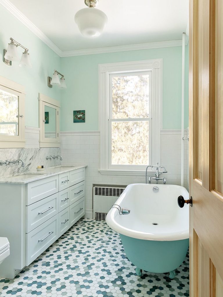 Hình ảnh phòng tắm với sàn lát gạch hình lục giác, tường sơn xanh nhạt, bồn tắm lớn, tranh treo tường