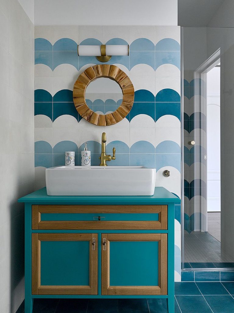 Hình ảnh một góc phòng tắm với gạch ốp màu xanh trắng kết hợp, khung gương bằng gỗ, tủ đựng màu xanh viền khung gỗ