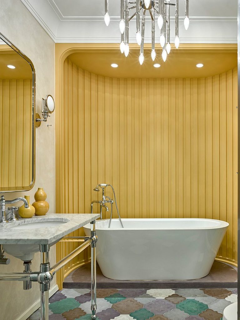 Hình ảnh một góc phòng tắm nhỏ với mảng tường cong sơn vàng bao quanh bồn tắm