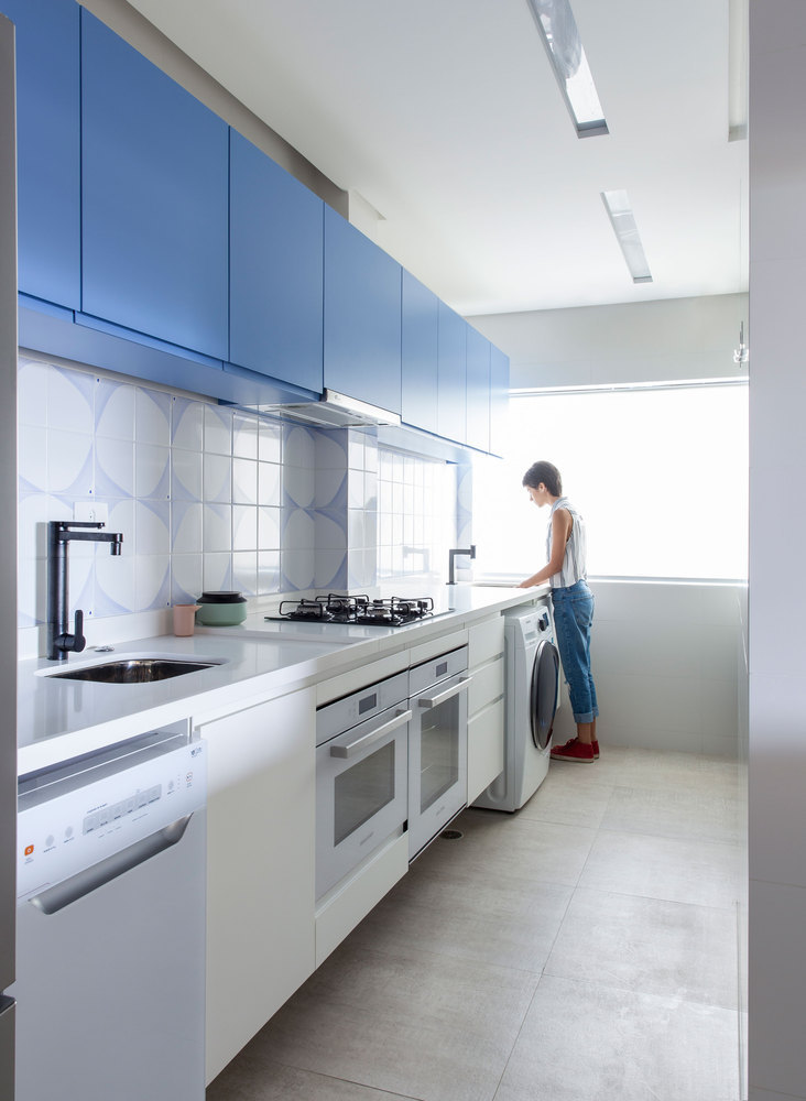 Hình ảnh một phòng bếp nhỏ đẹp với tủ màu xanh dương, người phụ nữ tóc ngắn đang đứng rửa bát