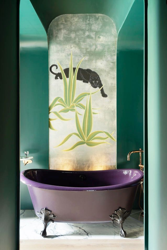 Hình ảnh phòng tắm ấn tượng với tường xanh lá đậm, tranh báo đen, bồn tắm màu tím