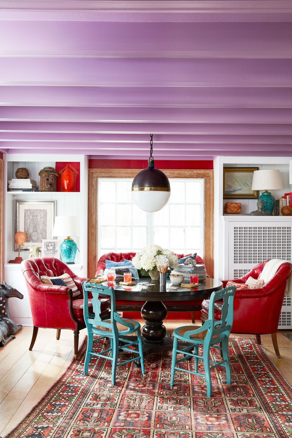 Phòng ăn được bài trí độc đáo với những chiếc ghế màu xanh ngọc lam, trần nhà màu tím, thảm trải thổ cẩm, ghế bành màu đỏ