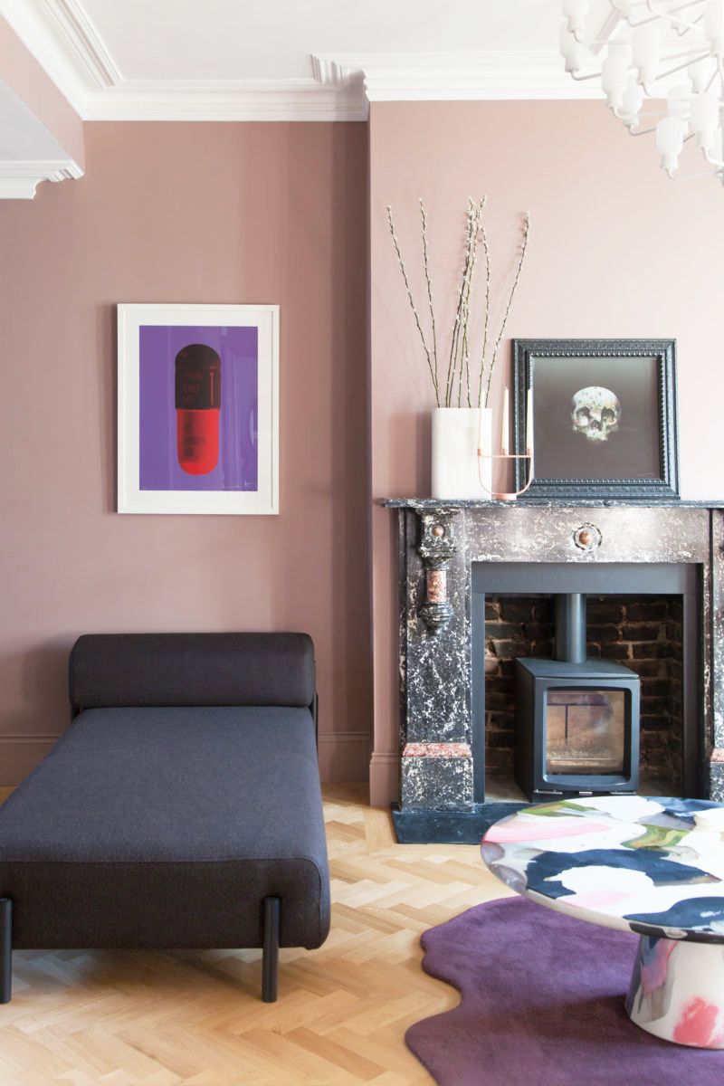Hình ảnh một góc phòng khách với tường màu hồng tro, sofa xanh than, thảm trải màu tím mộng mơ