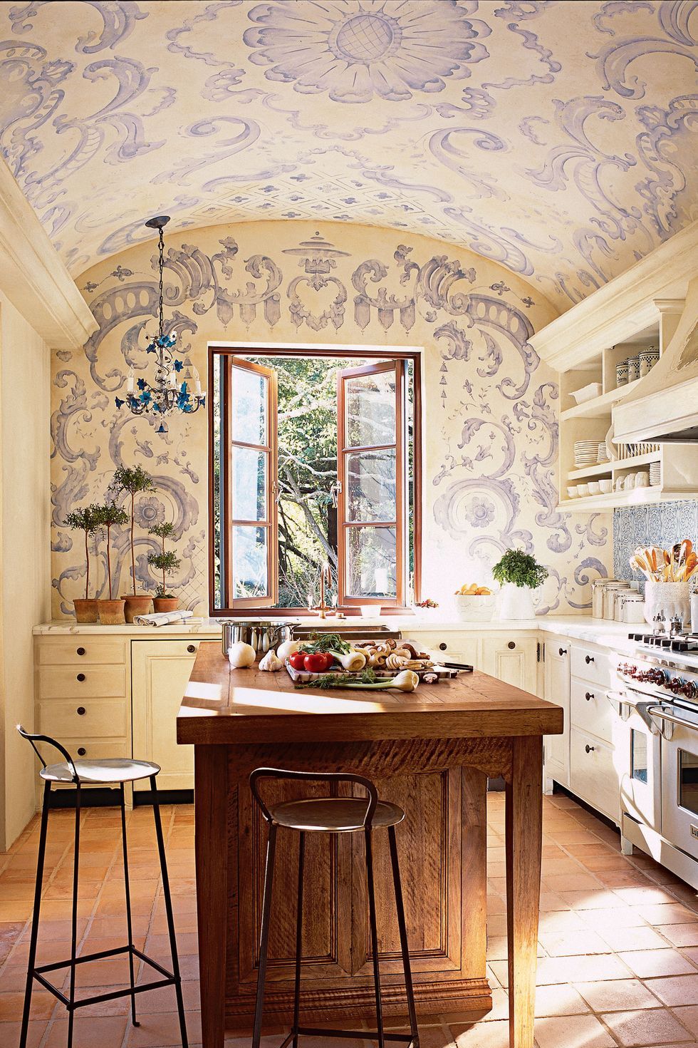 Hình ảnh một góc phòng bếp với bàn đảo bằng gỗ, giấy dán tường họa tiết tím, tủ ngăn kéo màu trắng