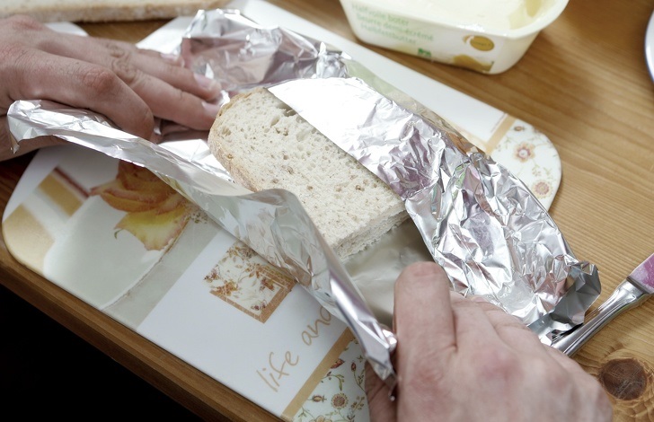 Hình ảnh đôi bàn tay đang mở bọc giấy bạc khỏi bánh mỳ gối