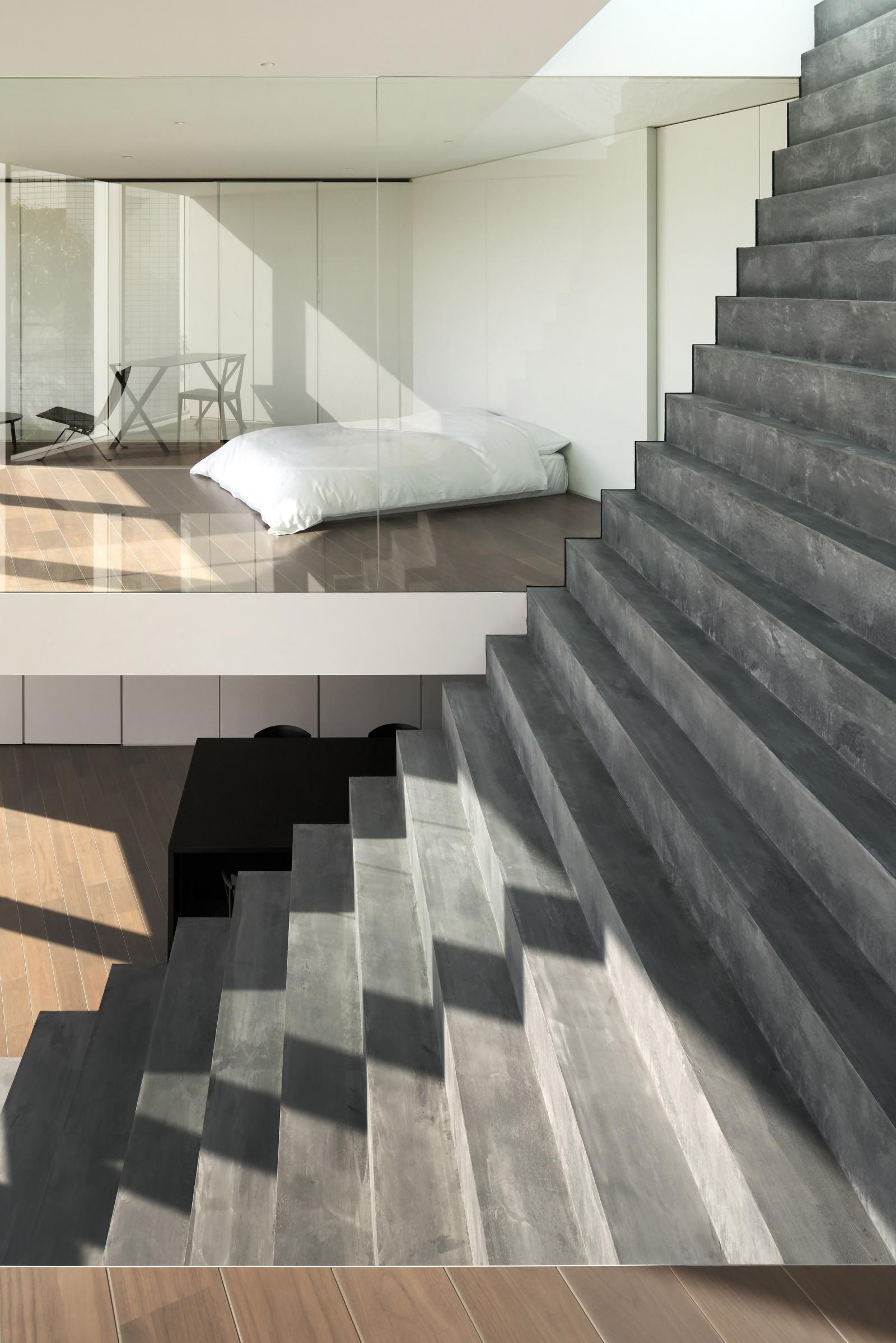 Hình ảnh phòng ngủ tối giản với giường nệm màu trắng cạnh cầu thang giả